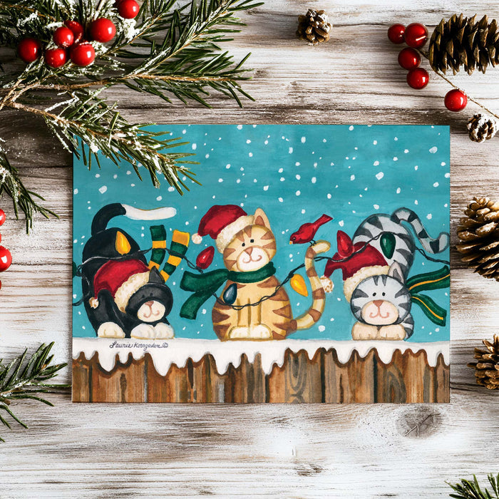Christmas-themed card with cats and holiday decorations on a wooden surface.