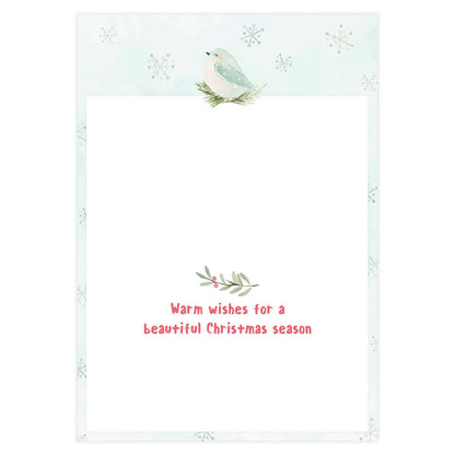 Holiday card with a bird and foliage design on a light blue background with snowflakes.