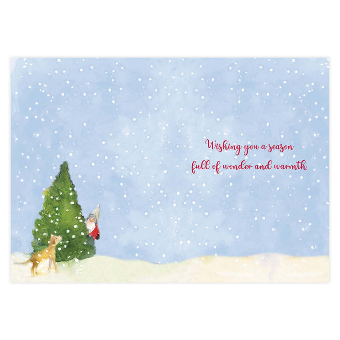 Christmas card with a snowy landscape, tree, and gnome with text 'Wishing you a season full of wonder and warmth'.